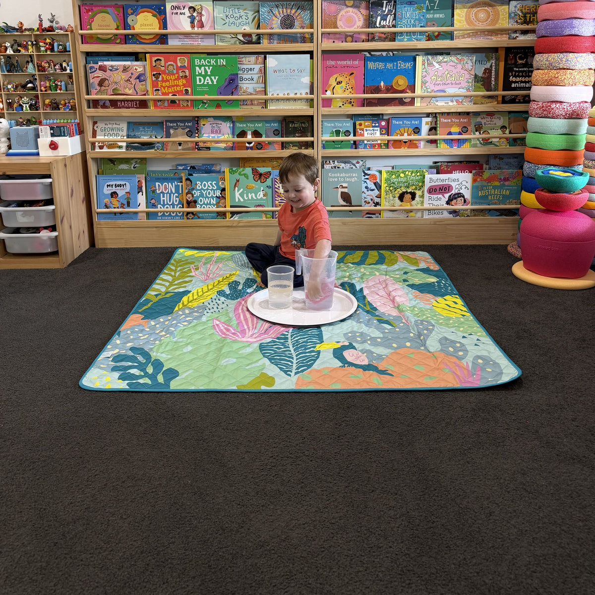 toddler doing water play on the flamingo-a-go-go large waterproof playmat in a playroom