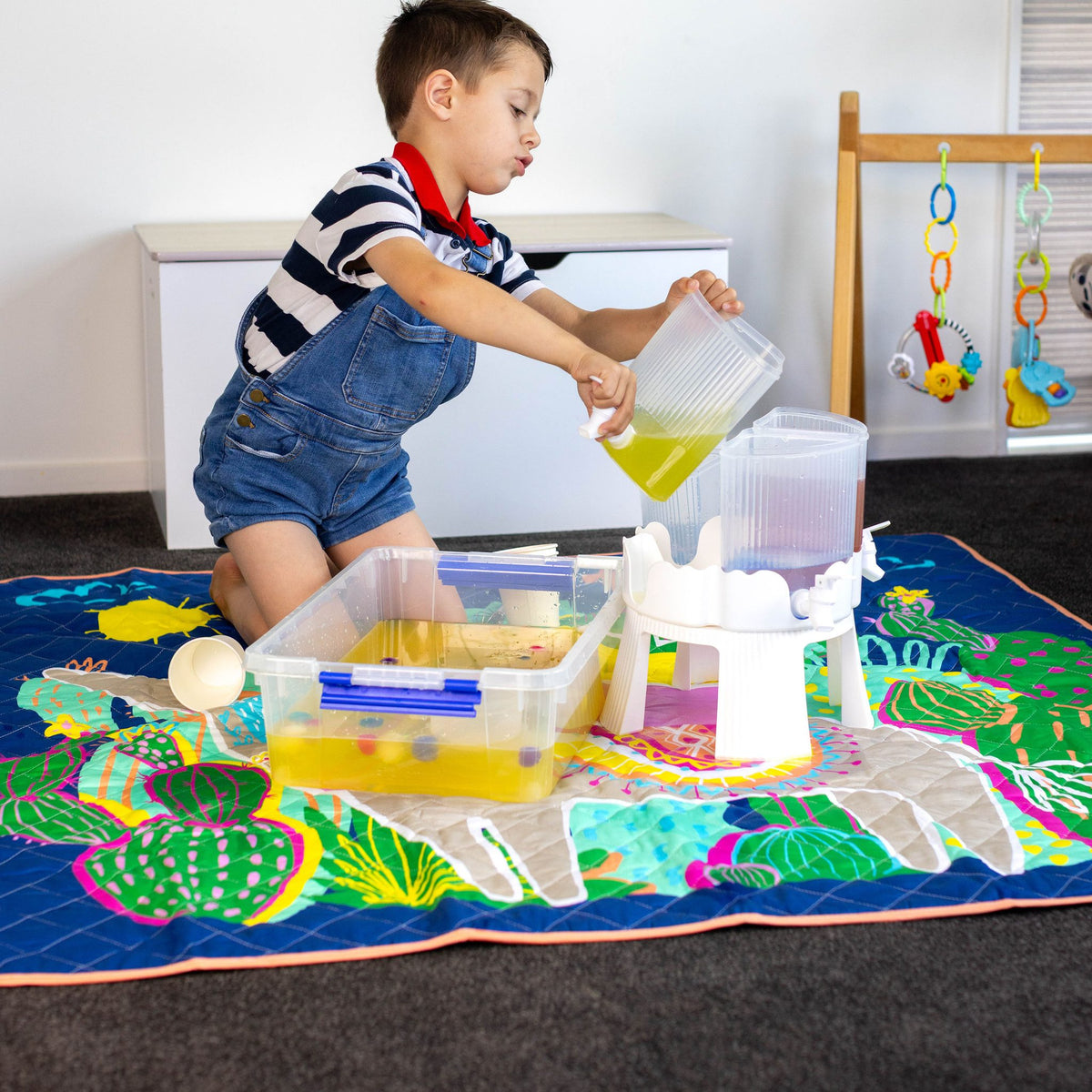 child pouring water during messy play on the hola mamacita large waterproof playmat