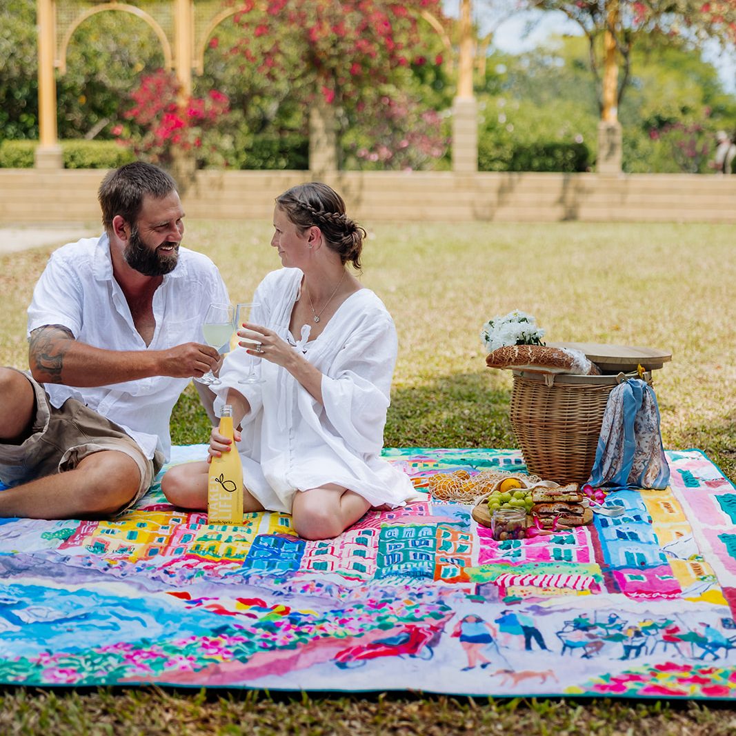 couple sharing a picnic on the la dolce vita waterproof picnic blanket in a garden