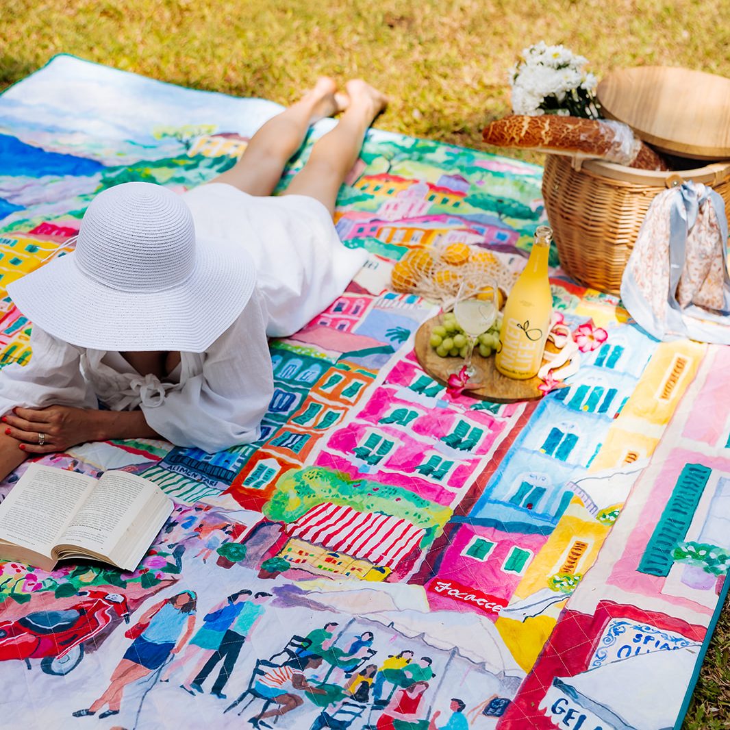 woman in a sun hat reading on the la dolce vita waterproof picnic blanket