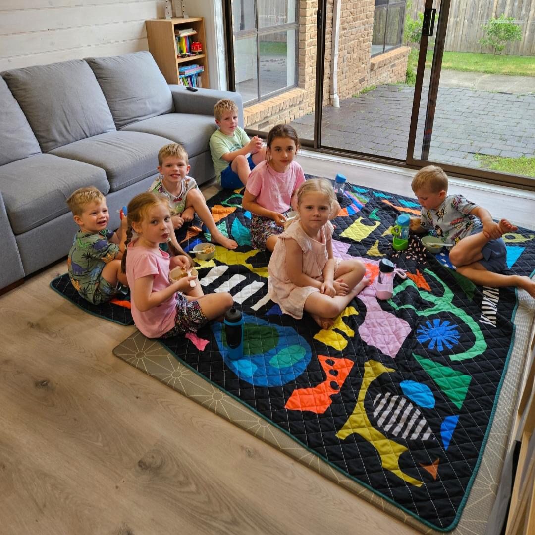 group of children having a snack on the rock candy waterproof picnic blanket indoors