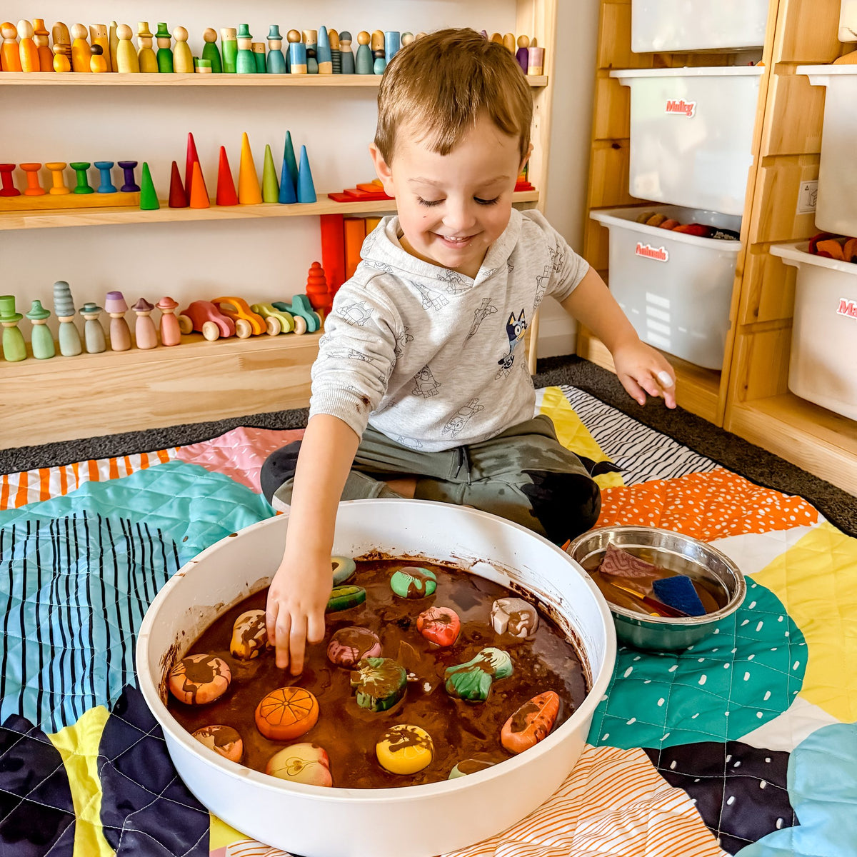 smiling toddler doing messy mud play on the happy now large waterproof playmat