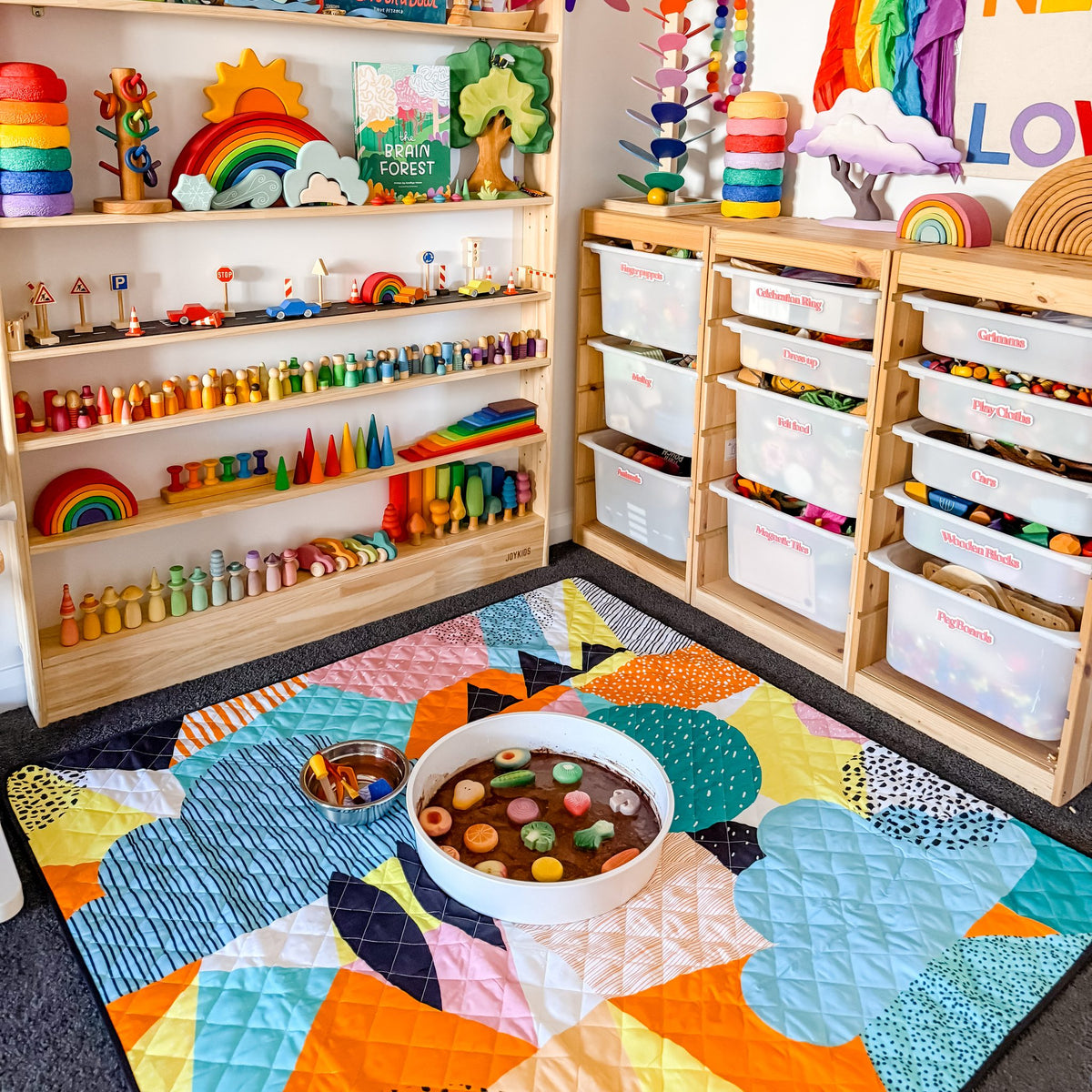 the happy now large waterproof playmat set up with a sensory tray in a bright playroom