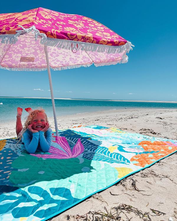 little girls enjoy time at the beach on her beach blanket