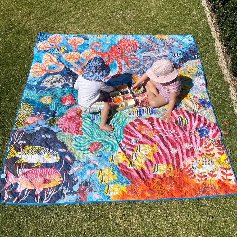 Kids eating a picnic on an octopus design play mat in the garden