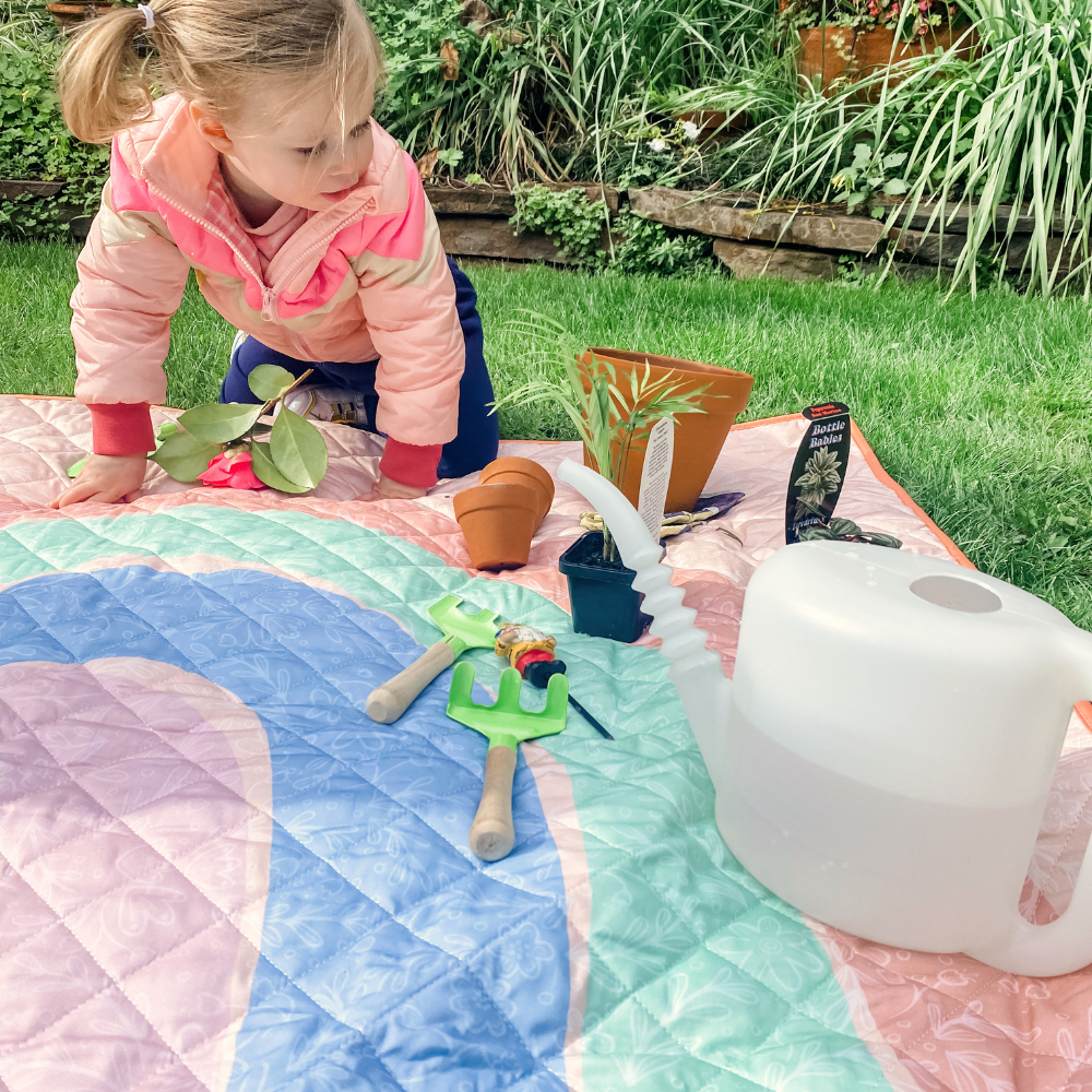 little girl playing with garden tools on play mat for garden