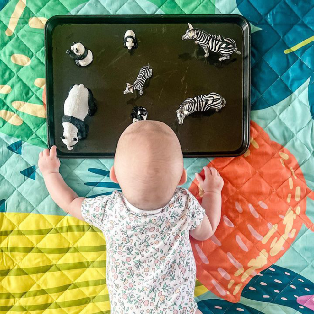 baby playing with toys on a picnic blanket