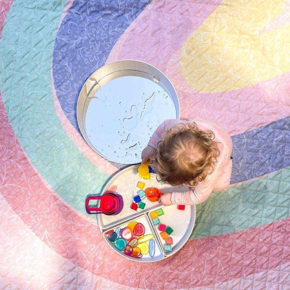 child playing with water toys on a mat messy play time