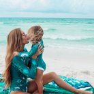 women and child enjoy the beach on a large beach blanket