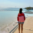 woman wearing the blush on red adventure backpack by the water