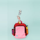 flat lay of the blush on red adventure backpack with snack pouches and drink bottles in the side pockets