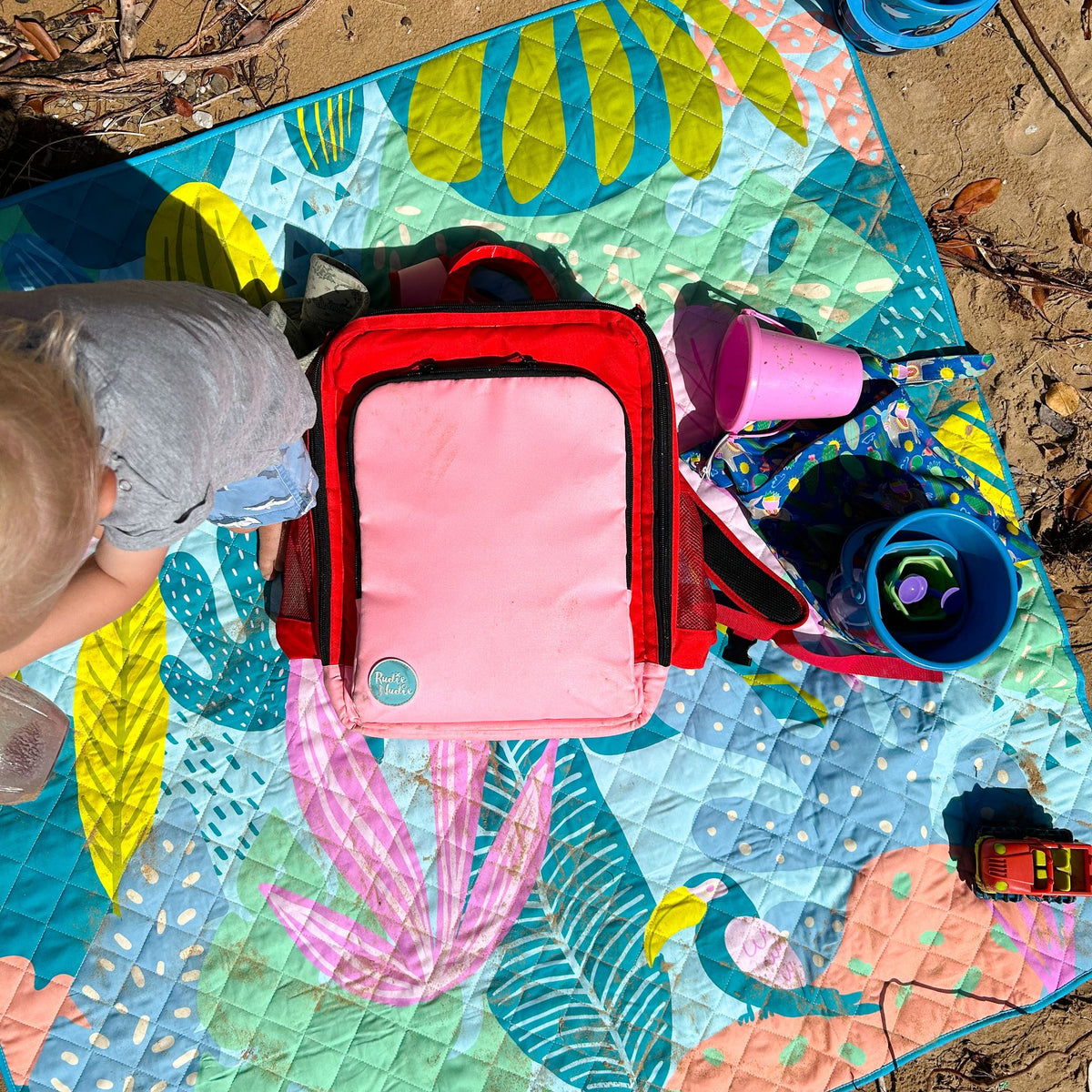 blush on red adventure backpack packed for a day out on a flamingo picnic blanket