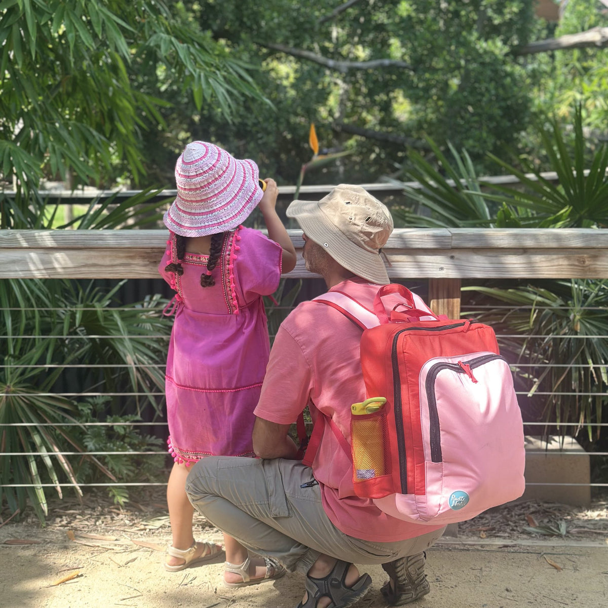 dad and daughter at the zoo with the blush on red adventure backpack