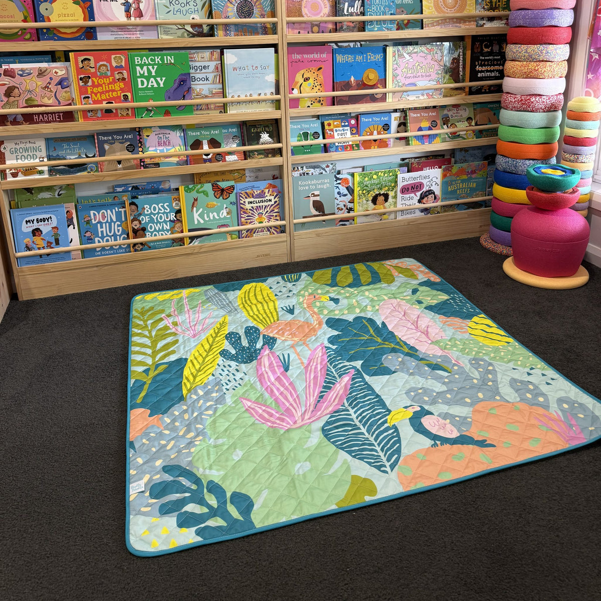 flamingo-a-go-go large waterproof playmat laid out in a bright playroom with bookshelves