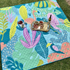 flamingo-a-go-go waterproof picnic blanket laid out on the lawn with a grazing platter