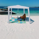 flamingo-a-go-go picnic blanket with umbrella hole under a beach cabana on white sand