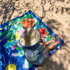 child eating watermelon on the hola mamacita large waterproof playmat on the sand