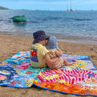 two children sitting together on the octopus's garden large waterproof playmat at the beach