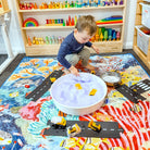 child playing with trucks and a sensory tray on the octopus's garden large waterproof playmat
