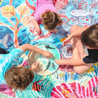 overhead view of three children doing sensory play on the octopus's garden waterproof picnic blanket