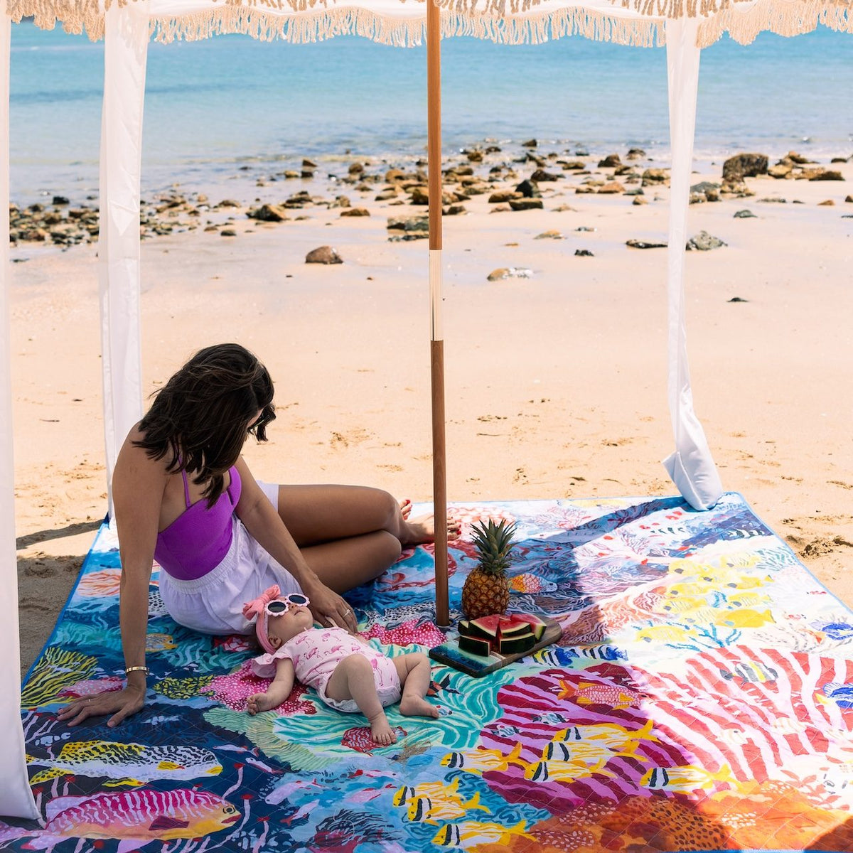 mother and baby under a beach cabana on the octopus's garden picnic blanket with umbrella hole