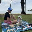 mother and toddler having a picnic on the pooch party large waterproof mat by the water