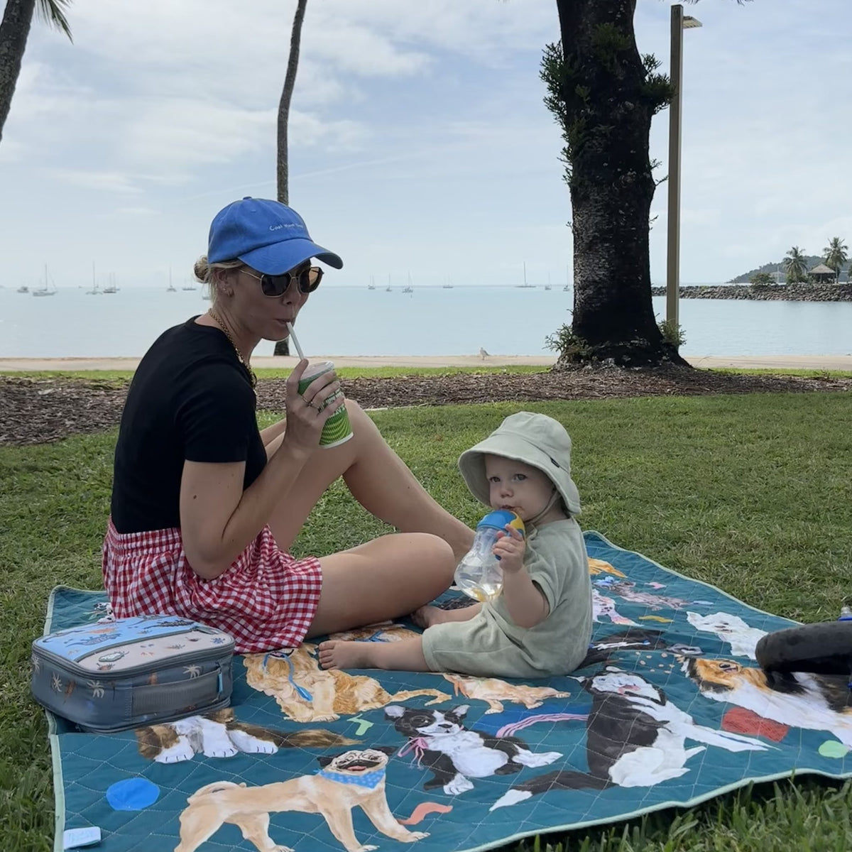 mother and toddler having a picnic on the pooch party large waterproof mat by the water