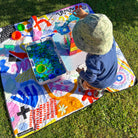 child doing sensory play on the pop pip pow large waterproof playmat on the lawn