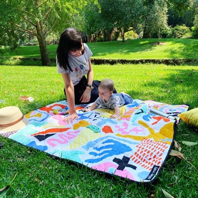 mother and baby doing tummy time on the pop pip pow large waterproof playmat in the park