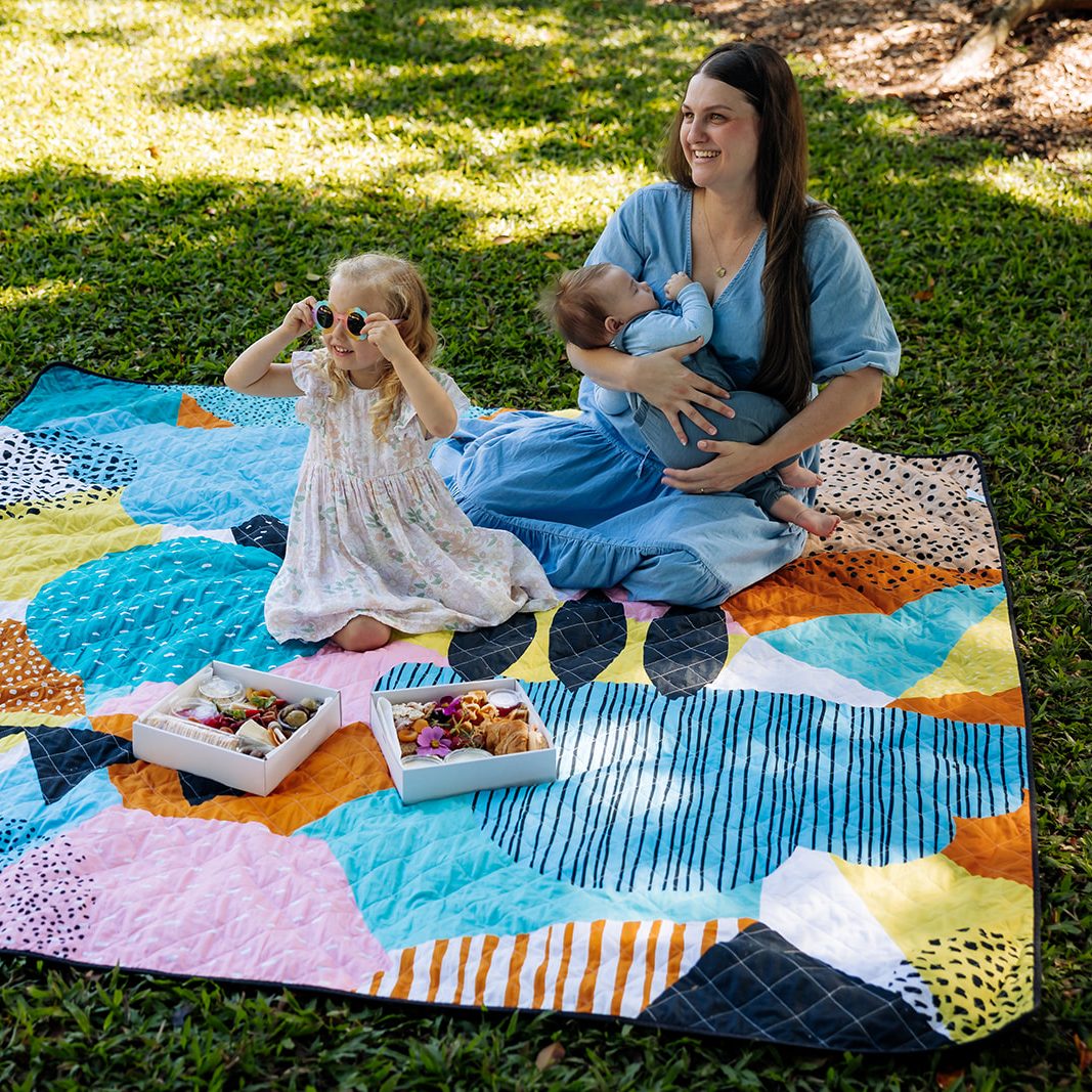 mother with baby and daughter on the happy now waterproof picnic blanket in the park