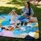 mother with baby and daughter on the happy now waterproof picnic blanket in the park