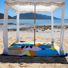 the happy now picnic blanket with umbrella hole under a fringed beach cabana