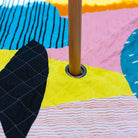 close-up of a timber umbrella pole through the middle of the happy now picnic blanket with umbrella hole