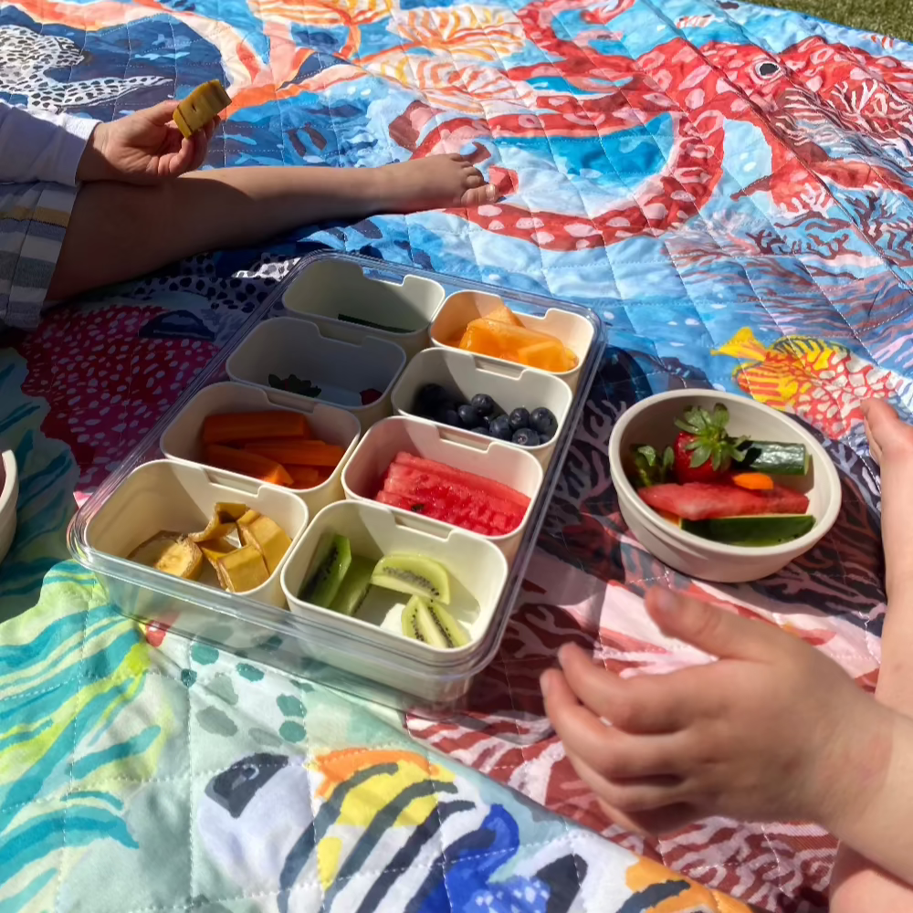 toddlers eating a picnic on octopus blanket in the garden