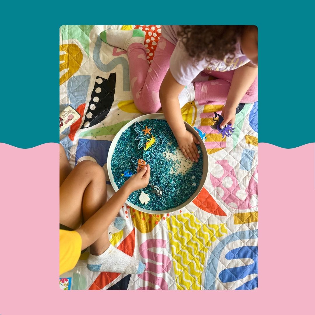 Child playing with coloured rice in the Jellystone Tray Play on a Rudie Nudie playmat